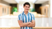 Young man smiling with his arms crossed.