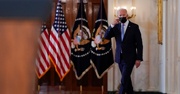 Biden walks into a room wearing a mask and prepares to give a speech 