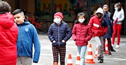 Kids wear masks as they line up outside of school