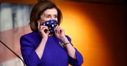 Nancy Pelosi holding a mask up to her face  