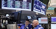 Two men looking at screens displaying stock information 