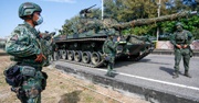A Taiwan military personnel looks on at a tank in the road with two other soldiers