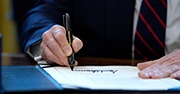 President Trump signing papers with a black marker 