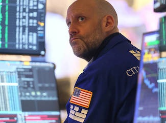 Floor trader grimacing in front of screens