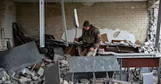 Soldier searching through rubble of a heavily damaged room