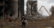 Woman walks past destroyed apartment towers in Mariupol